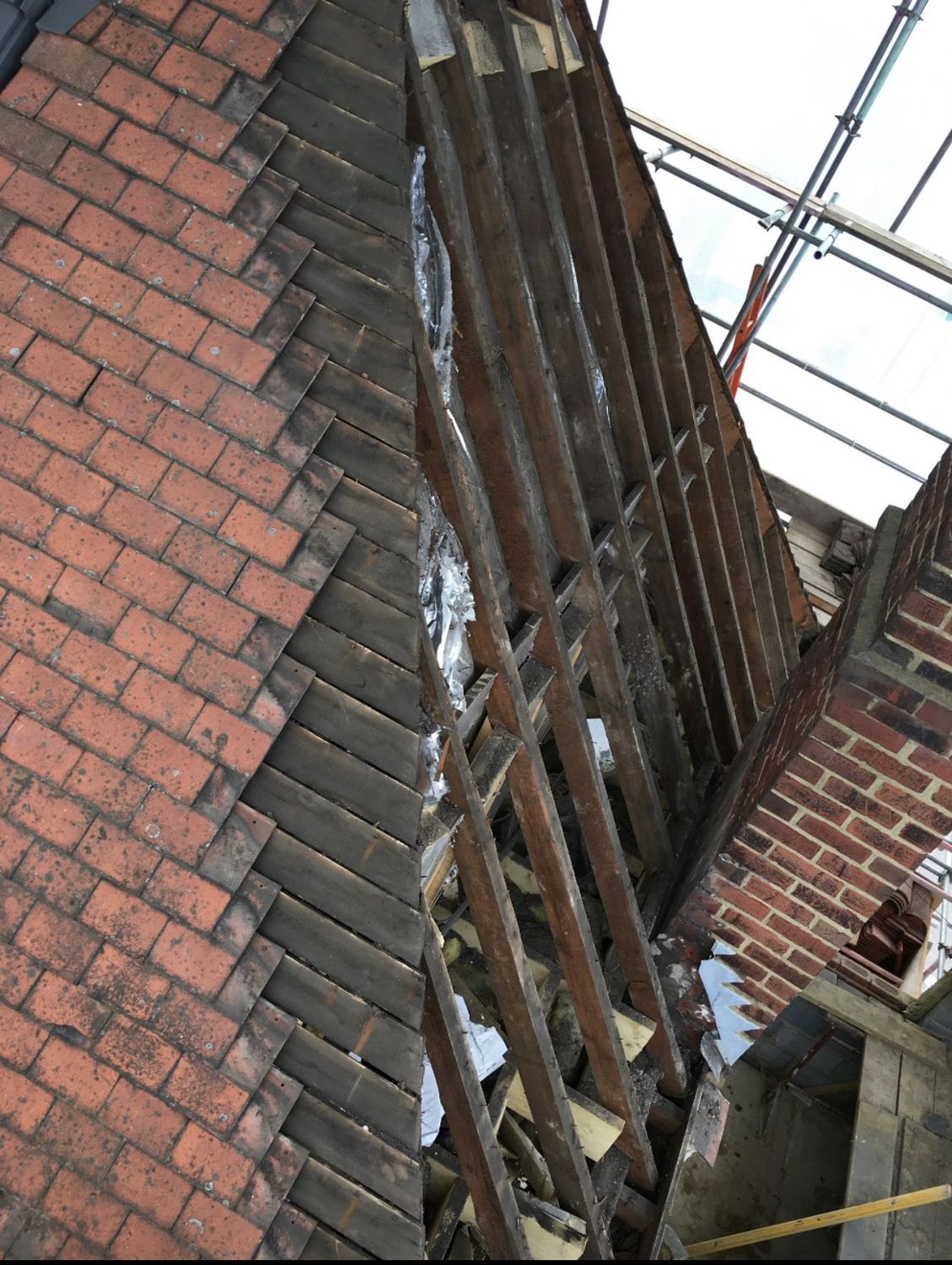 Old roof stripped back to the timbers beside a scaffold