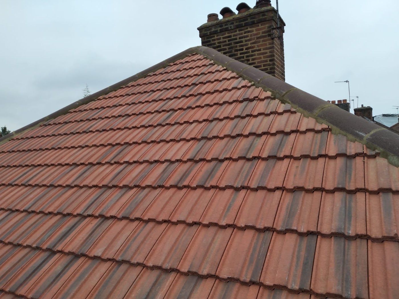 Newly tiled roof beside a brick chimney stack